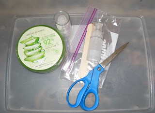 DIY tools for refilling airless pump bottles, including bottle, skincare product, scissors, ziploc bag, spatula, and q-tips