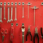 Handtools hanging on a red peg board.