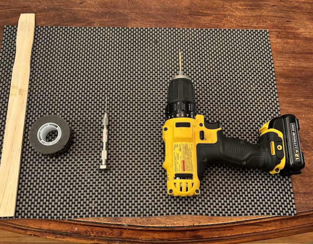 Tools for modifying a model train tank car's sound, including paint stick, tape, pin vise, and drill.