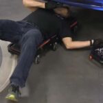 Mechanic using Eastwood rolling undercar tool tray to access tools while working under a car