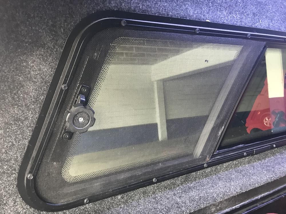 Side window of a vehicle, indicating the area for a DIY car fan installation, highlighting the crank handle that needs to be worked around.