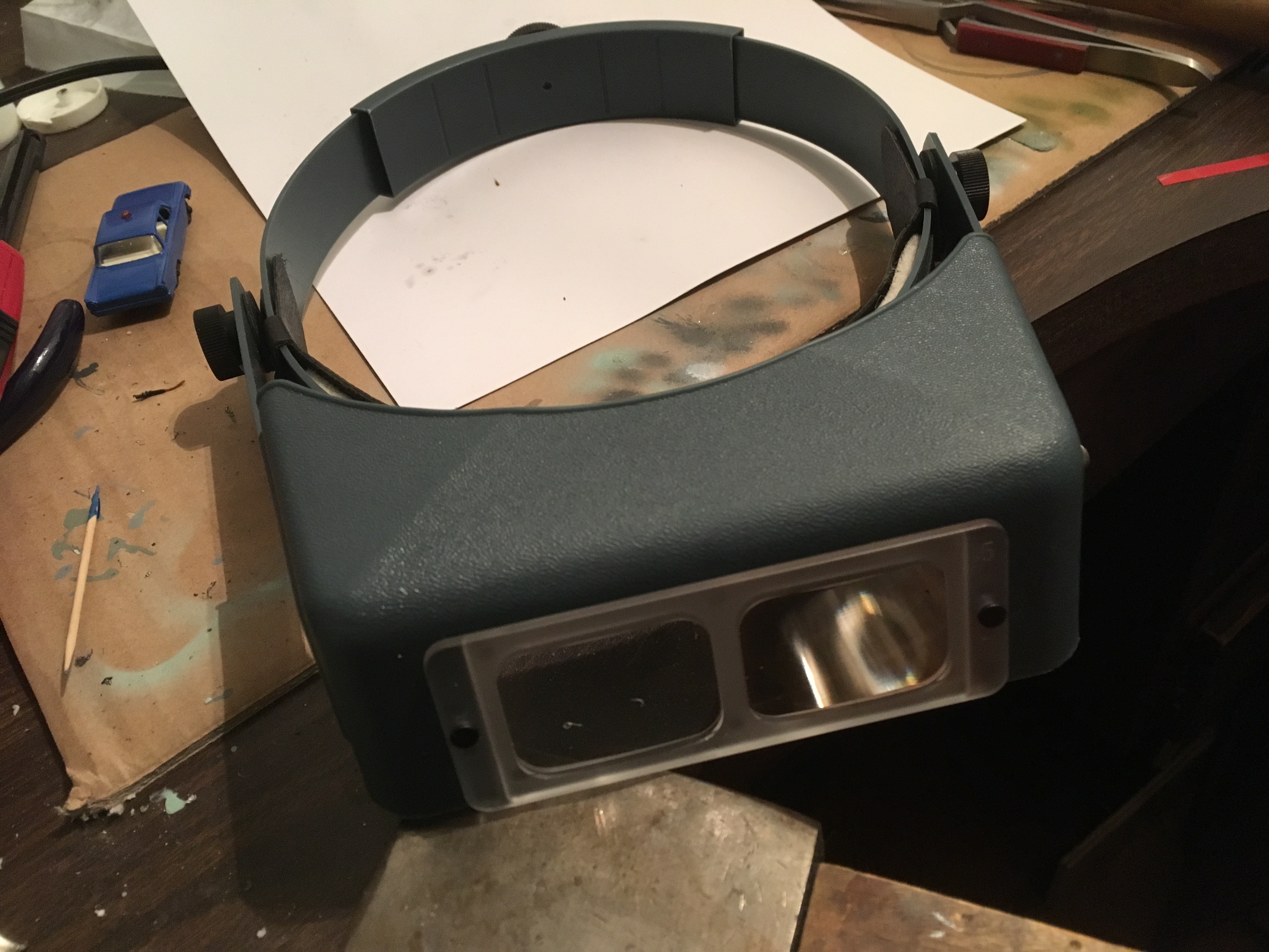 OptiVisor head-mounted magnifier with glass lenses providing clear and magnified vision for detailed toy car restoration work.