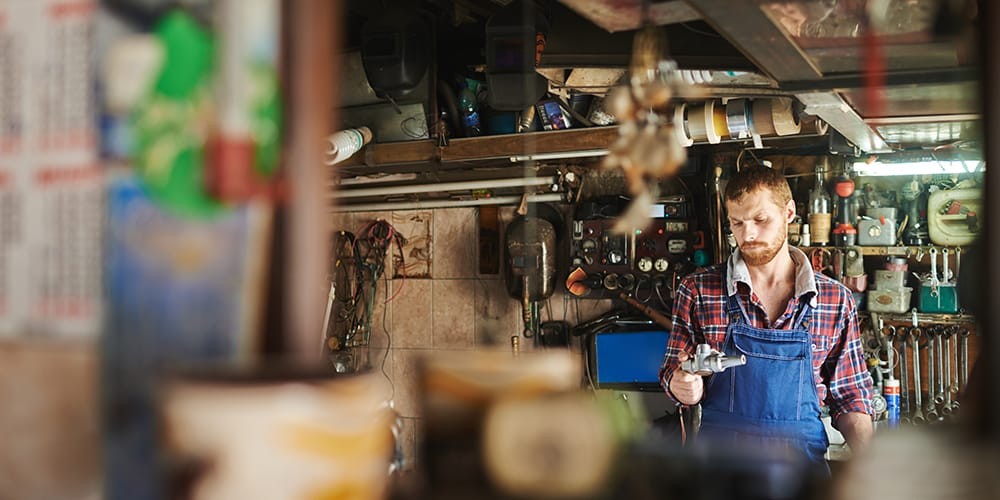 Professional mechanic inspecting car engine with tool