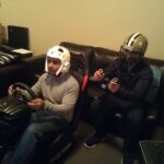 alt text: Two people playing a racing simulator game