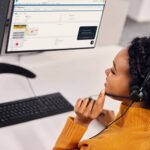 alt text: A woman wearing a Jabra Engage 50 headset is working at her desk in an office setting.